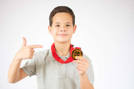 Young boy showing his golden medal over white background.の写真素材