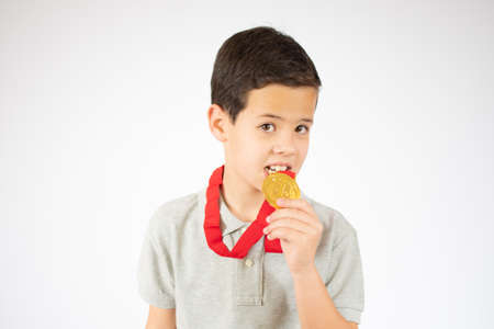 Young boy testing the golden medal over white backgroundの写真素材