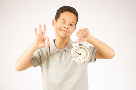 childhood, fashion and people concept - portrait of boy with alarm clock over white backgroundの写真素材