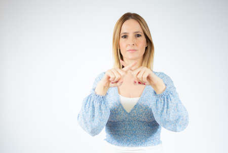 Young woman wearing blue shirt standing over white isolated background rejection expression crossing...