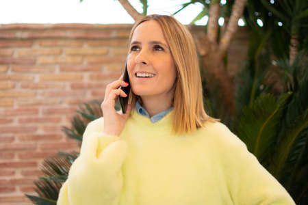 Portrait of young woman talking with mobile standing outdoorsの写真素材