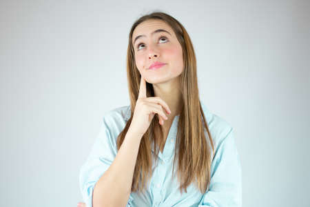 Young woman over isolated white background thinking an idea while looking up