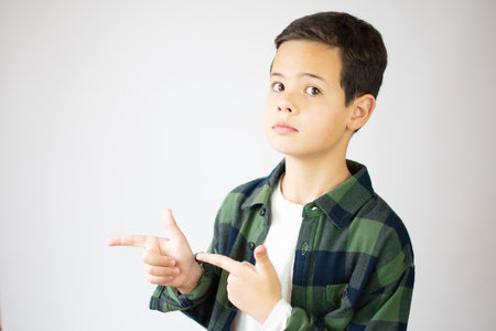 Beautiful young boy pointing index fingers aside up over white backgroundの写真素材