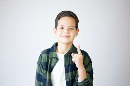 Portrait of cheerful boy with good idea - isolated over white background. 10 year old kid pointing finger up. Child points by finger upward. Cheerful boy shows somethingの写真素材