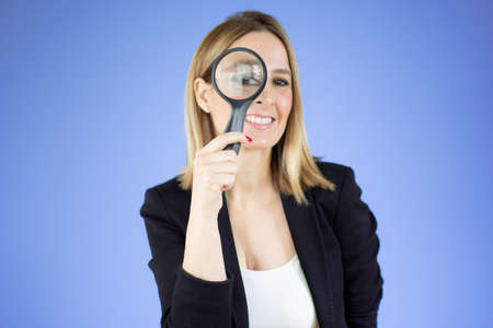Business woman holding magnifying glass behind eyes. smiling business woman isolated portrait.の写真素材