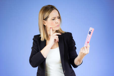 Portrait of young office woman with calculator looking aside and holding finger at cheek isolated...