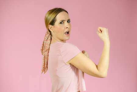 Successful woman raising hand in success gesture over pink background