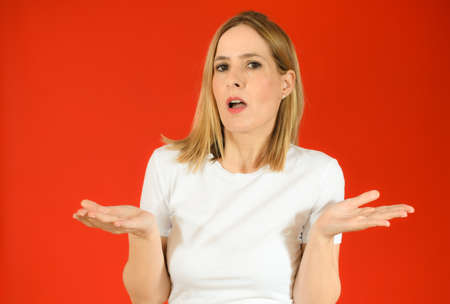 Young woman standing over red isolated background clueless and confused expression with arms and...