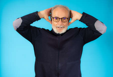 Amazed older man in casual sweater isolated over blue backgroundの写真素材