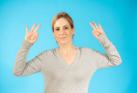 Young beautiful woman wearing casual sweater standing over blue isolated background smiling positive...