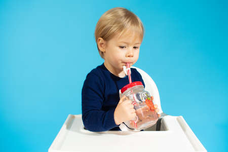 Baby boy holding a glass against a blue background