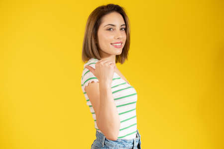 Smiling pretty young woman showing thumb up isolated over yellow backgroundの写真素材
