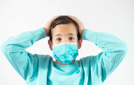 Handsome brunette boy in medical mouth mask over white backgroundの写真素材