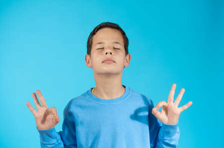 Pensive child with blue sweater isolated on blue backgroundの写真素材