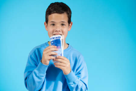 Surprised little boy with money cash. Cute kid hiding face behind fan of money bills. Lottery winner, businessman, success. Money saving. Money for future education.の写真素材
