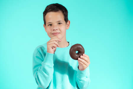 Young boy with donuts is happy about sugar snack that makes his childhood joyful and sweetの写真素材