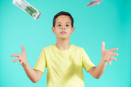 Surprised little boy with money cash. Cute kid hiding face behind fan of money bills. Lottery winner, businessman, success. Money saving. Money for future education.の写真素材