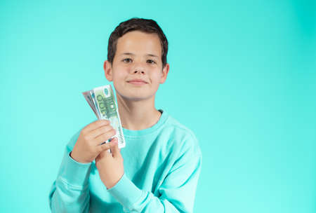 Surprised little boy with money cash. Cute kid hiding face behind fan of money bills. Lottery winner, businessman, success. Money saving. Money for future education.の写真素材