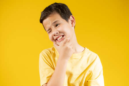 Boy with yellow t-shirt making gesture over yellow backgroundの写真素材