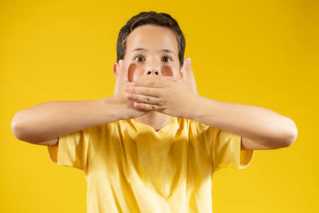 Little boy kid wearing casual clothes shocked covering mouth with hand for mistake. secret concept.の写真素材