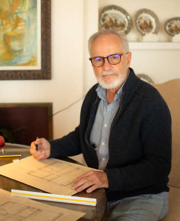 Older man drawing some plans at homeの写真素材