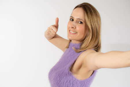 Close up portrait of smiling pretty young woman showing thumb up isolated over white backgroundの写真素材