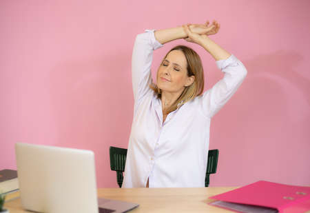 Business woman relaxing with hands behind her head and sitting on an office chairの写真素材