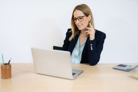 Concentrated young beautiful business woman working on laptop in office