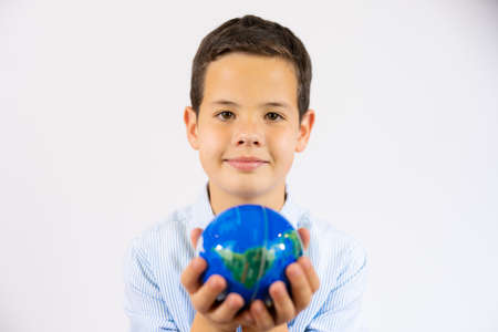 Closeup portrait of school boy holding a world globe isolated over white backgroundの写真素材