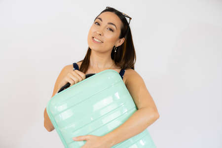 Young traveler woman holding a suitcase isolated over white backgroundの写真素材