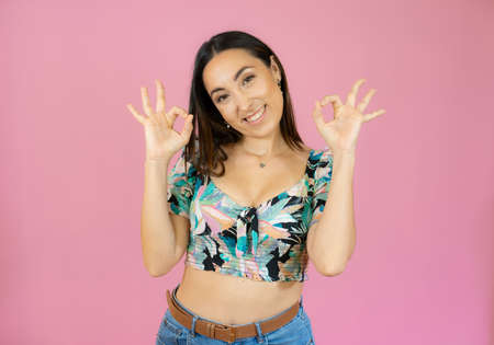 Young beautiful woman wearing casual shirt standing over pink isolated background smiling positive...