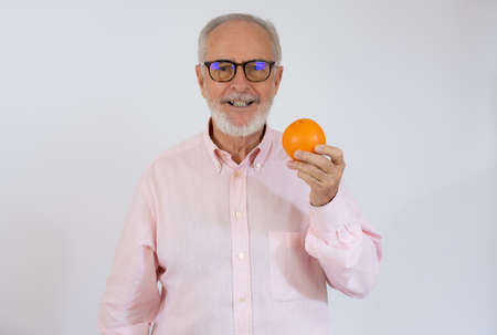 Portrait of cheerful senior man who is holding orange and smiling.の写真素材