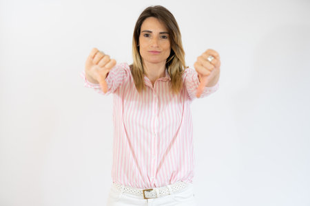 Young woman over isolated white background showing thumbs down with negative expressionの写真素材