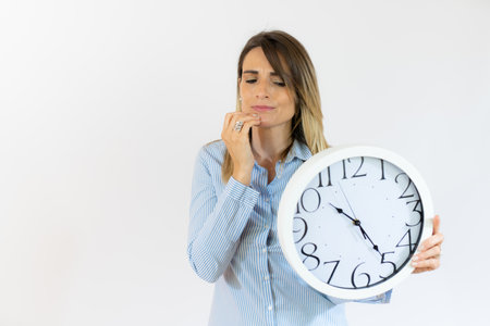Business woman holding alarm clock with pensive gesture standing over isolated white background.