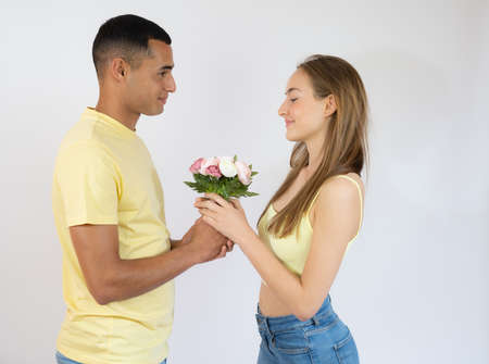 handsome man giving pink flower bouquet to woman isolated over whiteの写真素材