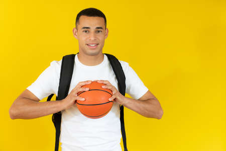 happy handsome student holding a basketball isolated over white background.の写真素材