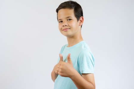 Let's hug. Portrait of friendly hospitable little boy in black T-shirt smiling happily and holding hands wide open to embrace, welcome. indoor studio shot isolated on blue backgroundの写真素材