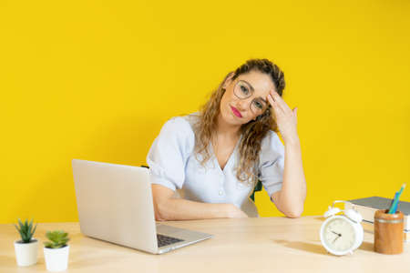 Worried woman working on computer laptop over yellow background.の写真素材