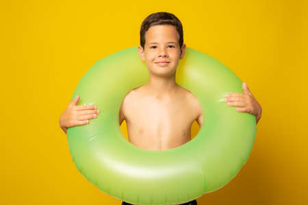 cute little boy holding a swim ring isolated on yellow backgroundの写真素材