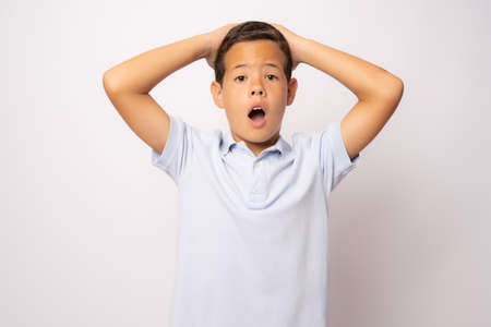 Amazed or surprised child boy hand holding hairs on head isolated over white background.の写真素材