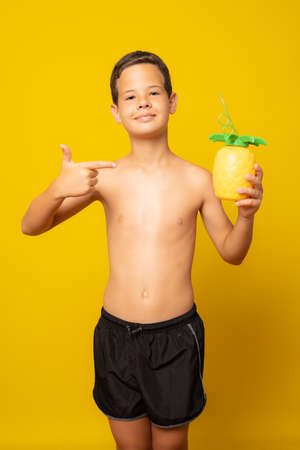 Cute boy in swimwear holding a juice isolated over yellow background.の写真素材