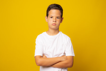 Cute boy in white t-shirt with arms folded isolated over yellow background.の写真素材