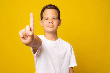 Portrait of cheerful boy with good idea isolated over yellow backgroundの写真素材