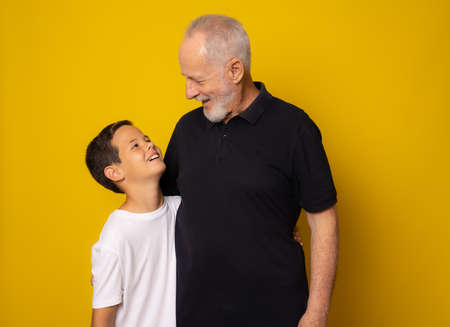 Grandfather and grandson smiling over yellow background