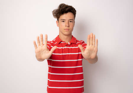 Young man in striped polo shirt with stop hands gesture isolated over white background.の写真素材