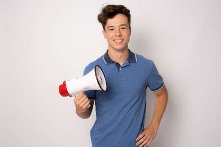 Handsome young man over isolated white background holding a megaphoneの写真素材