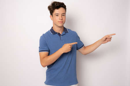 Young man in casual clothing showing product with hand isolated over white background.の写真素材