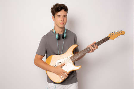 young man in headphones playing the guitar over white background.の写真素材