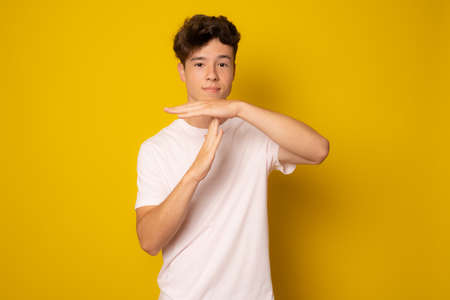 Young caucasian man wearing casual t-shirt doing time out gesture with handsの写真素材