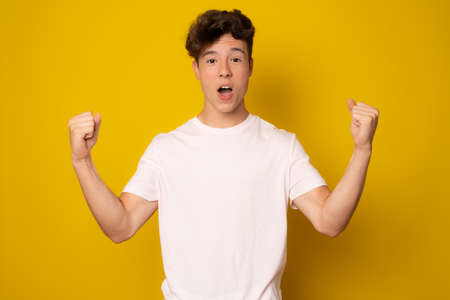 Lucky young man isolated over yellow background